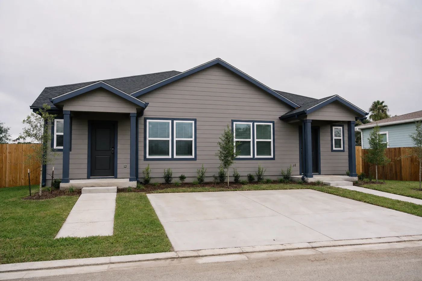 Newly completed workforce duplex rental home with navy trim and a shared concrete driveway
