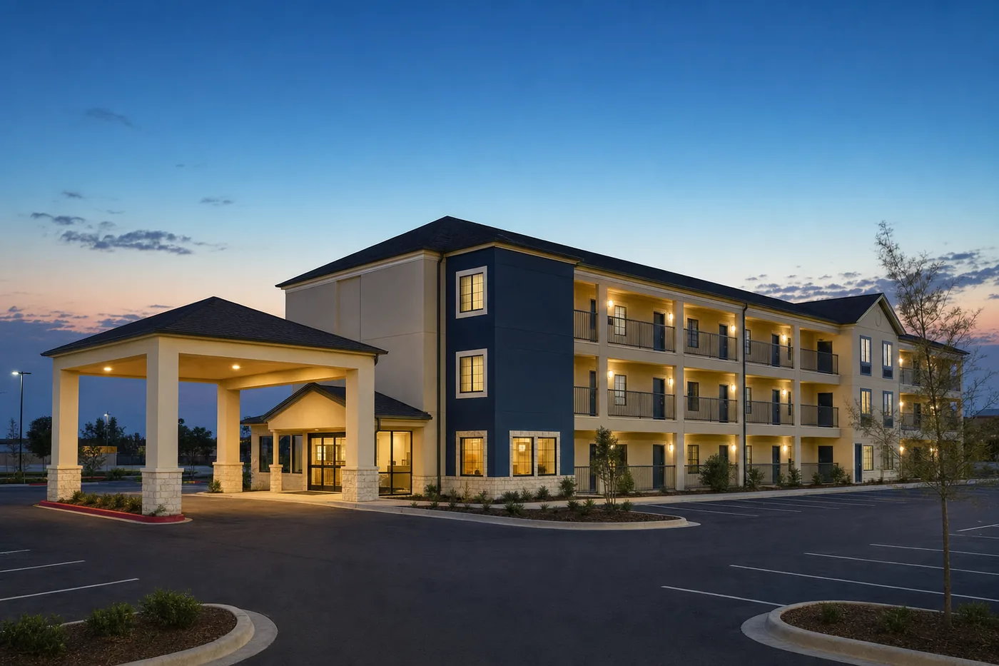 Three-story economy extended-stay lodging building at dusk on a Texas highway corridor